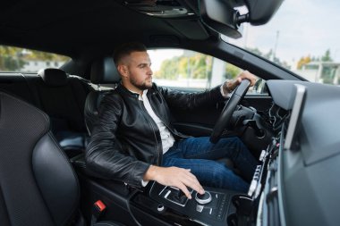 Başarı devrede. Deri ceketli yakışıklı genç adam araba kullanıyor. İçeriden bak. Yüksek kalite fotoğraf