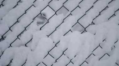 Karla kaplı tel örgü, kar birikintisinin yarattığı geometrik desenlere odaklanıyor. Yüksek kalite 4k görüntü