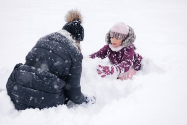 Anne ve kızı birlikte karlı bir günün tadını çıkarıyor, anılar yaratıyor ve güzel bir manzarada kış neşesini paylaşıyorlar. Yüksek kalite fotoğraf
