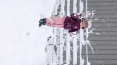 Kışlık kıyafetlerle sarılıp, karlı bir harikalar diyarında oynayan sevimli genç kız. Karla kaplı ağaçların arasında durmuş, karlı bir günün büyüsünü yakalıyor. Yüksek kalite 4k görüntü