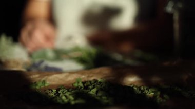 Kadın balmumu kağıdından kurutulmuş nane yaprağı alıyor. Bitkilerle dolu tabağa odaklan. Ağır çekim. Yüksek kalite 4k görüntü