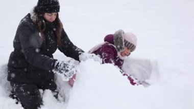 Karda oynayan bir anne ve kızın sevgi ve kış aile bağlarını yakalaması ne kadar da iç açıcı. Yüksek kalite 4k görüntü