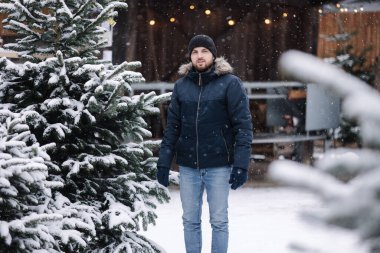 Yakışıklı sakallı adam panayırda bir Noel ağacı seçiyor..