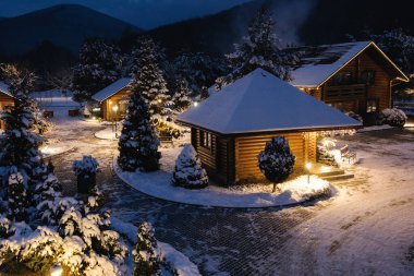 Dağlarda yuva yapmış, ışıldayan ışıklar ve huzurlu kış cazibesiyle karlı bir köyün tepeden görünüşü. Yüksek kalite fotoğraf