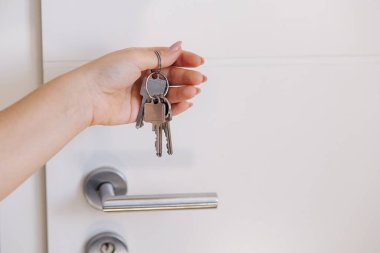Anahtarları elinde tutan kişi beyaz bir kapıyı kilitlerken ya da açarken, yakın çekim. Yüksek kalite fotoğraf