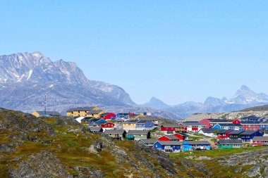 Grönland 'ın başkenti, Grönland' ın en büyük adası Nuuk 'ta, dünyanın kıyısındaki kayalık dağların arka planına karşı renkli geleneksel evlerle dolu Grönland yaz manzarası.