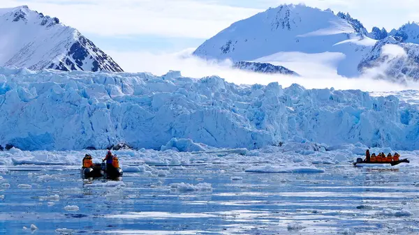 Buzul ve karla kaplı dağların arka planında turistlerle dolu kutup manzarası