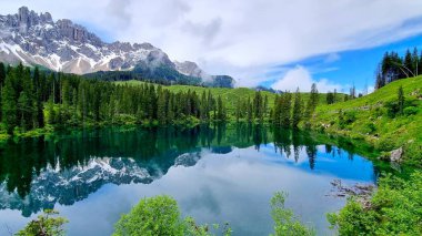 İtalya 'nın güneyindeki Dolomitler' de Carezza Gölü 'ndeki karla kaplı dağ tepelerinin yansımalarıyla resim gibi bir manzara.