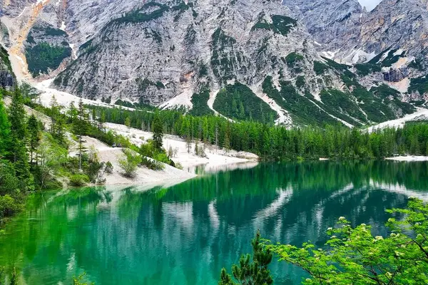 Kayalar, dağ gölü, Lago di Braies ve Güney Tyrol, İtalya 'daki yansımaları ile göz kamaştırıcı bir manzara.