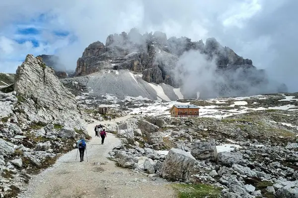 Dolomitler, İtalya - 16 Haziran 2024: Laghi-dei-Piani gölünün kıyısındaki tanınmayan genç çiftin Güney Tyrol 'daki Tre Cime Doğa Koruma Alanındaki güzel manzaraya hayran kalmaları