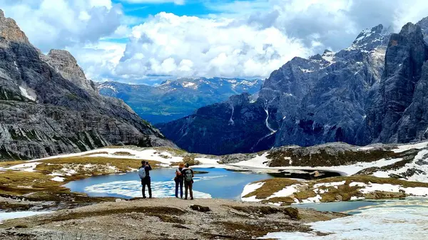 Dolomitler, İtalya - 16 Haziran 2024: Laghi-dei-Piani gölünün kıyısındaki tanınmayan genç çiftin Güney Tyrol 'daki Tre Cime Doğa Koruma Alanındaki güzel manzaraya hayran kalmaları
