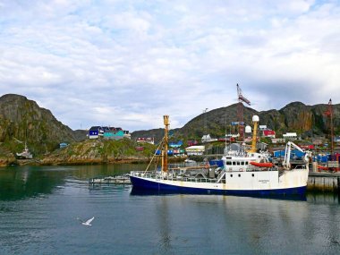 Maniitsoq, West Greenland - July 6, 2019: Scenic view of fishing port with fishing boats and colorful Inuit houses on rocky seashore against beautiful cloudy sky in early summer morning in the Greenlandic Venice clipart