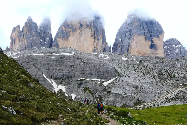 Dolomitler, İtalya - 16 Haziran 2024: Tre Cime di Lavaredo 'nun kuzey duvarları ve dairesel rotadaki bir grup tanınmayan turistin manzarası Güney Tyrol' daki en ünlü ve popüler yürüyüş merkezlerinden biridir.