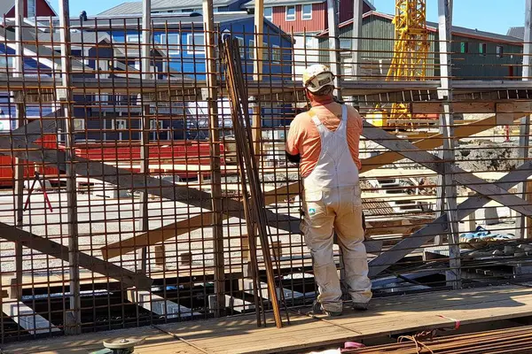 Nuuk, Grönland - 3 Temmuz 2019: Tulumlu ve başlıklı tanınmayan bir işçi güçlendirilmiş beton bina yapılarında kullanmak üzere takviye ağ veya çerçeve yapmakla meşgul