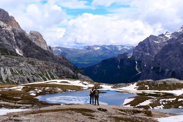 Dolomitler, İtalya - 16 Haziran 2024: Laghi-dei-Piani 'nin Alp gölleri yakınlarında tanınmayan genç bir çift manzaraya hayran 