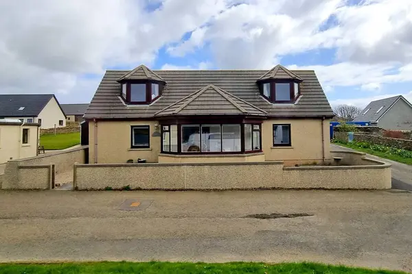 Orkney Adaları 'nda geniş bir defne penceresi ve iki yurt penceresi olan küçük bir kırsal ev manzarası 