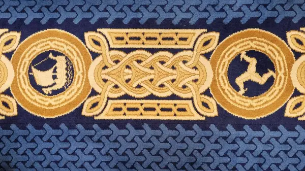 Douglas, Man Adası - 22 Nisan 2024: Tynwald 'da bir zemin halısının deseni ve Viking gemisi figürleri içeren ve adanın sembolü olan üç yüzlü İngiliz hükümdarlığı.