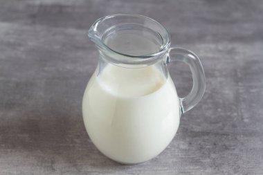 Gri arka planda bir sürahi süt