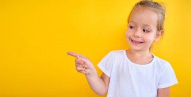 Smiling preschool girl showing , pointing at copy space for advertising text, big sale announce