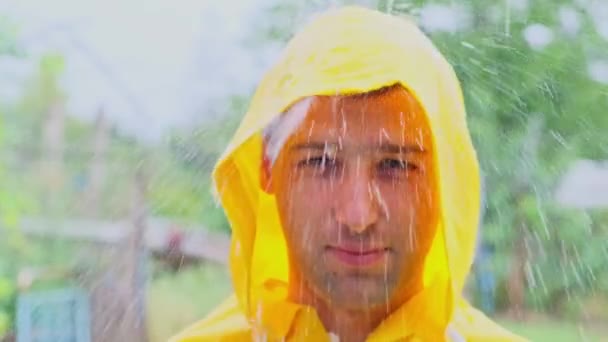 大雨の中黄色のレインコートを着た青年の前で — ストック動画