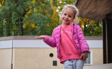 Parktaki sonbahar pembe giysilerinde avuç içi boş el duygusunu elinde tutan küçük kız. Yüksek kalite fotoğraf