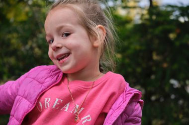 Yeşil şehir parkında gülümseyen sevimli küçük bir kızın portresi. Yüksek kalite fotoğraf