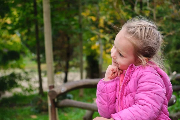Park yeşili arka planda, çene altında pembe ceket giyen sevimli bir çocuk. Yüksek kalite fotoğraf