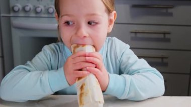 Küçük kız evde fast food yiyerek mutfağın tadını çıkarıyor. Yüksek kalite 4k görüntü