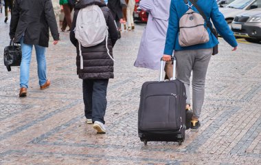 travel woman pulling suitcase backpack walking along sidewalk outdoors in modern urban city pathway pavement . High quality photo