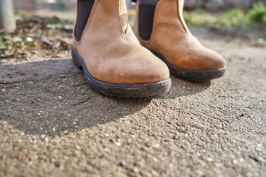 pair of handmade used childrens shoes on gray stone in a forest or park. High quality photo