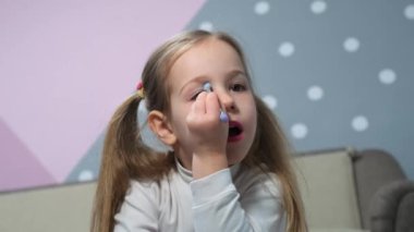 Little girls have fun make-up using brush apply shiny shadows on eyelids beauty. High quality 4k footage