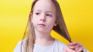 Mother tie tying fixing daughters little girl hair in a ponytail yellow background. High quality 4k footage