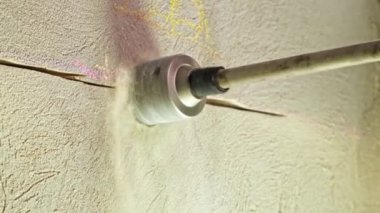 Bir erkek işçi elinde matkapla duvarda bir oyuk açıyor. Dairenin kaplama prizine elektrik prizi takıyorum. Yüksek kalite 4k görüntü