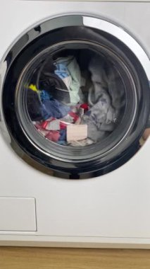 Çevirme döngüsü sırasında çeşitli kıyafetlerle dolu önden yükleme makinesinin yakın çekimi.