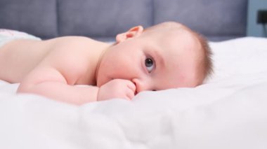 Yan görünüş başparmak emme küçük bebek erkek çocuk uyumadan önce kameranın parmaklarına bakıyor. Yüksek kalite 4k görüntü