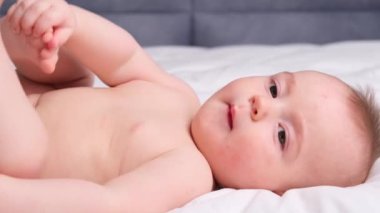 Küçük, küçük bir erkek bebek. Çocuklar bacaklarıyla oynuyor. Yatmadan önce arka odasında yatıyor. Çocuk banyo ve duştan sonra. Bebek cilt bakımı. Yüksek kalite 4k görüntü
