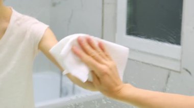  Kadın, ev temizliği ve temizlik hizmetlerinde aynayı bez ve spreyle temizleyip parlatıyor. Yüksek kalite 4k görüntü