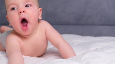 Yeni doğan, uyuyan, şaşkın küçük çocuk karnının üzerine uzanmış hafif bir yatakta annesine gülümsüyor. Bebek başını tutmayı öğreniyor. Yatma vakti. Yüksek kalite 4k görüntü