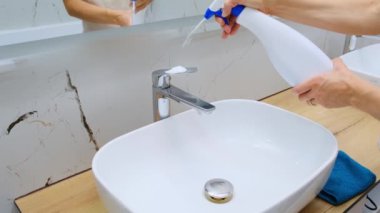 Kadınlar banyoda ev işleri yapıyor, lavabo ve musluğu sprey köpük deterjanıyla temizliyor mikrofiber sünger dezenfekte konseptiyle temizliyor. Yüksek kalite 4k görüntü