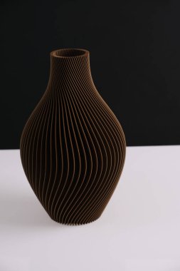 Geri dönüşümlü plastik izole edilmiş siyah arkaplandan çiçekler için yapılmış geometrik desenli dekoratif vazo içeren üç boyutlu yaratıcı teknoloji baskılı kahverengi vazo ev dekorasyonu. Yüksek kalite fotoğraf