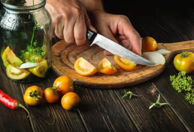 Konserve sebze salatası. Aşçı elleri bıçakla domatesleri kesiyor. Köylü yemeği..