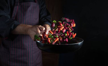 Şef kızartma tavasında sebze hazırlar. Bir restoranın mutfağında beslenme çanağı uçuşu. Otel için sebze menüsü.