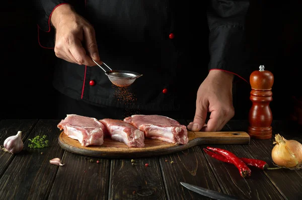 stock image The cook sprinkles fresh ribs with paprika close-up. Dark background for a recipe book or menu in a hotel.