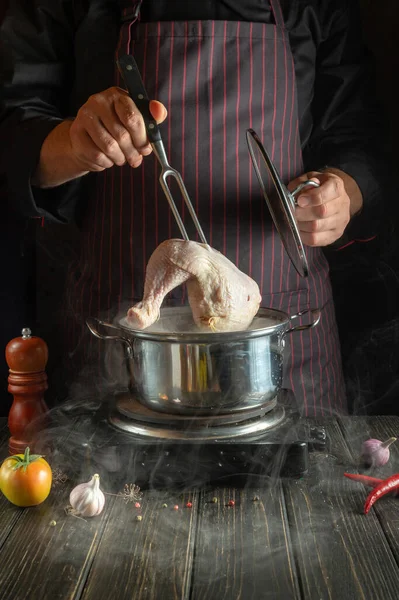 Professional chef cooks a chicken leg in a pot with vegetables. Recipe for a delicious lunch for a restaurant or hotel