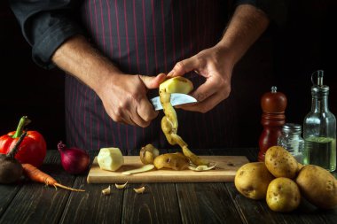 Şef mutfakta patates temizliyor. Lezzetli yemekler hazırlarken bıçaklı bir aşçının elleri. Restoran veya otel için sebze diyeti menüsü.