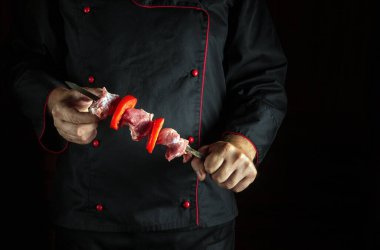 Profesyonel şef elinde şişte çiğ et ve sebzeli bir barbekü tutuyor. Asya ulusal mutfağı