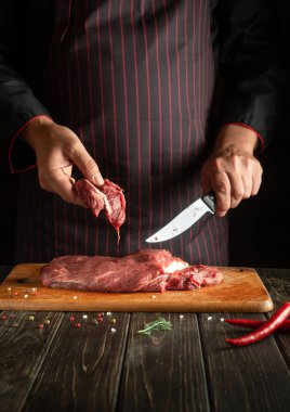 Mutfaktaki aşçının elleriyle taze et pişirmek için kesiyorum. Restoran veya otel için menü tarifi fikri