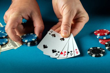 Poker kulübündeki mavi masada oturan bir oyuncunun elinde dört farklı kombinasyonla kazanma başarısı.