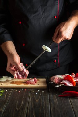Aşçı şişte çiğ et yiyor. Mutfakta bir şefin elleriyle şiş kebap pişirme işlemi.