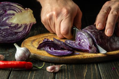 Şef kırmızı lahanayı bıçakla keser. Restoranın mutfağında sebze salatası pişiriyorum. Sebze diyeti fikri.